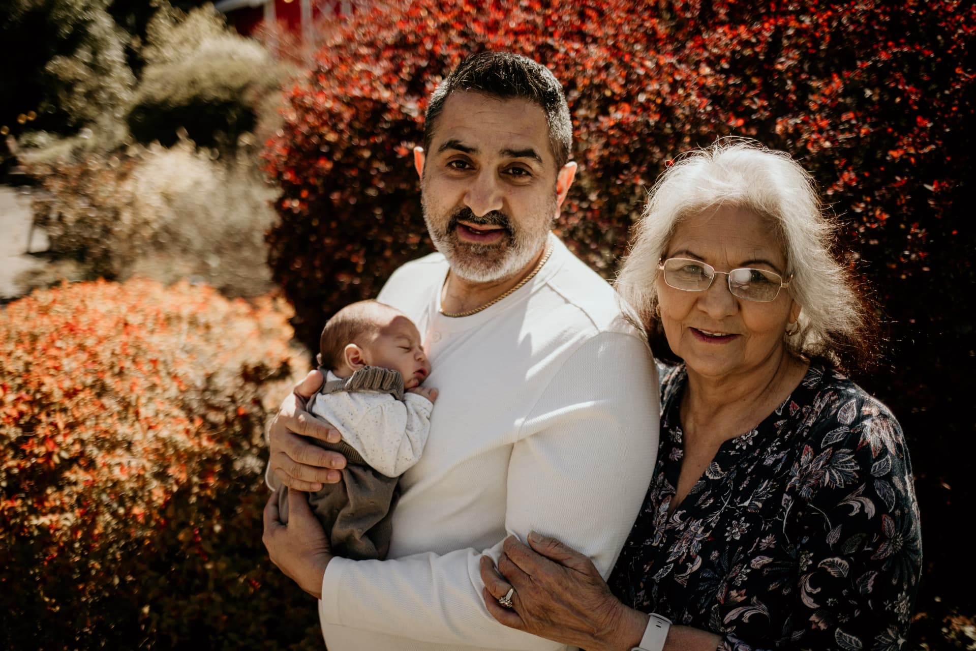 Mike Manhas holding his newborn daughter beside his mother